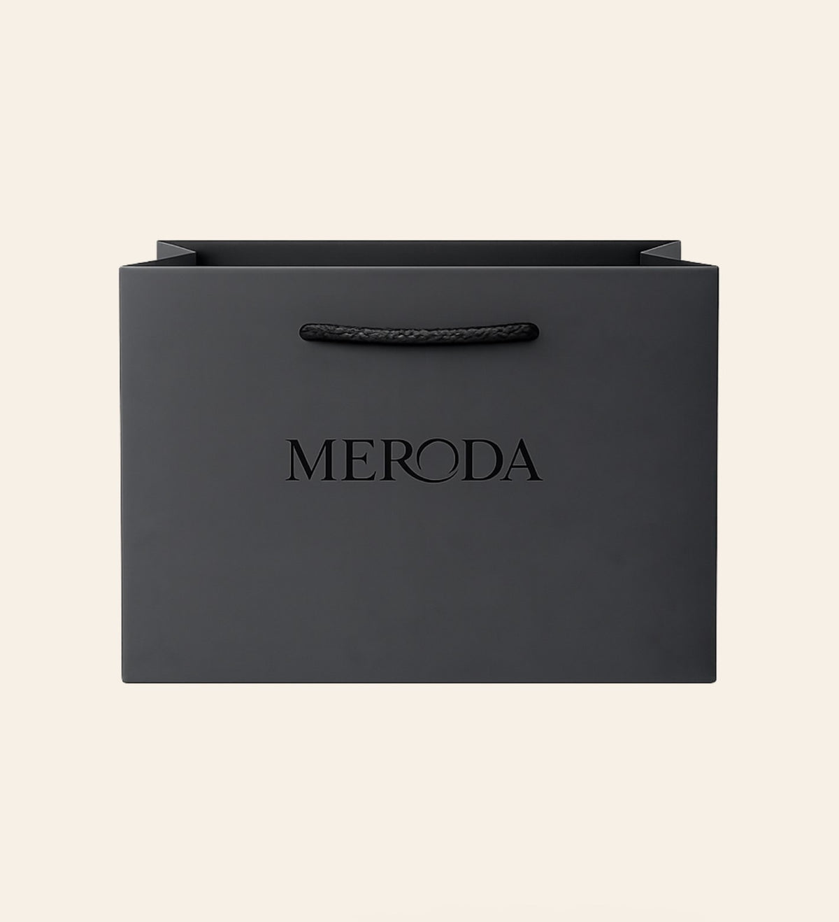 Mattschwarze Geschenktasche mit Kordelgriff und geprägtem Meroda-Logo vor cremefarbenem Hintergrund.