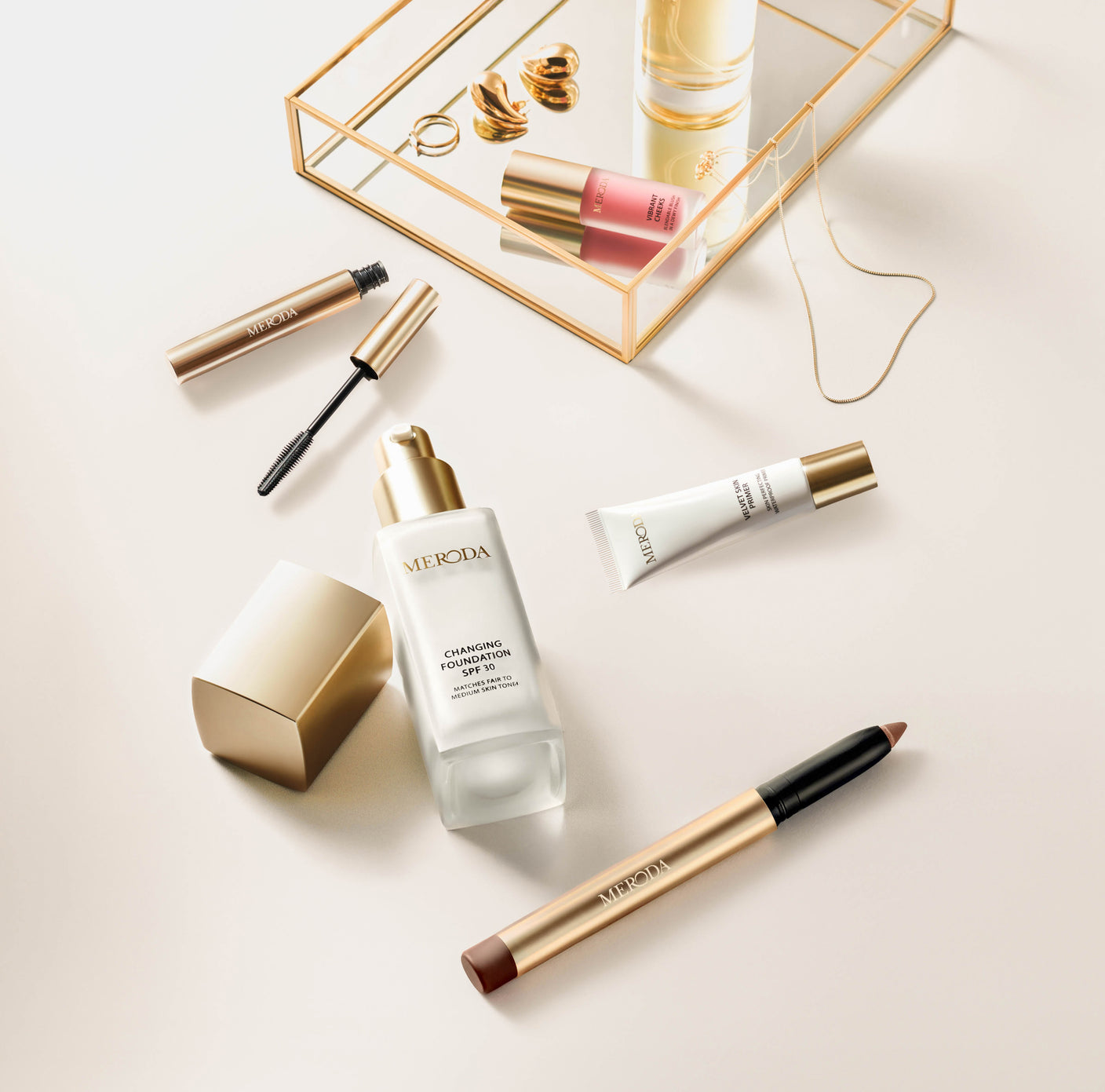 Essential Duo (+3 Gratisgeschenke) mit Changing Foundation, Eye Perfecting Shimmer Stick, Mini Gilded Lashes Mascara, Mini Velvet Skin Primer und Vibrant Cheek Blush auf hellem Hintergrund