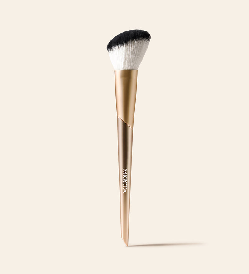 Meroda Cosmetics Vibrant Cheeks Blush Brush mit goldenem Griff und abgeschrägten Borsten vor hellem Hintergrund
