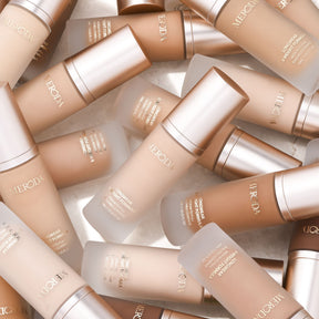 Meroda Cosmetics Universal Foundation Flaschen in verschiedenen Farbtönen auf hellem Hintergrund