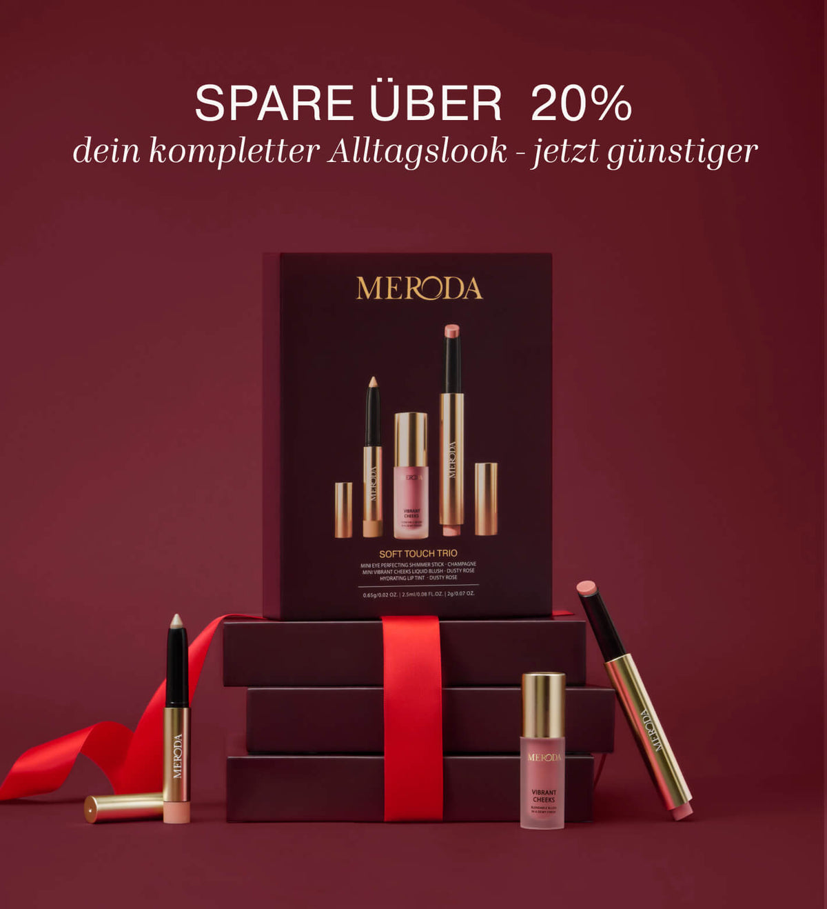 Soft Touch Trio Make-up-Set mit Eye Shimmer Stick, Liquid Blush und Lip Tint präsentiert vor Geschenkboxen mit rotem Band.