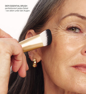 The Essential Brush mit goldenem Griff beim präzisen Verblenden unter den Augen eines Models