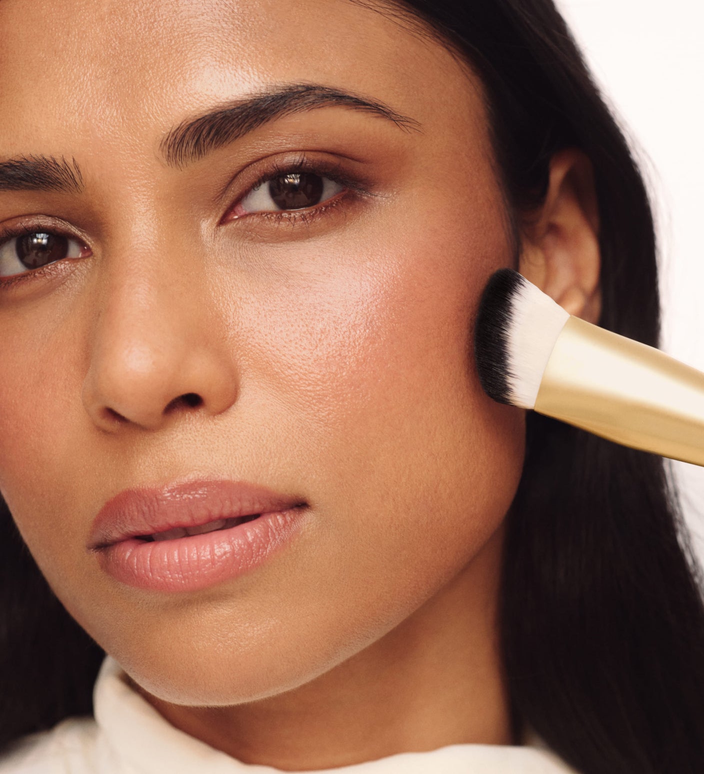 Model verblendet Make-up auf der Wange mit dem The Essential Brush für ein nahtloses, ebenmäßiges Finish.