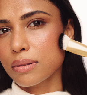 Model verblendet Make-up auf der Wange mit dem The Essential Brush für ein nahtloses, ebenmäßiges Finish.