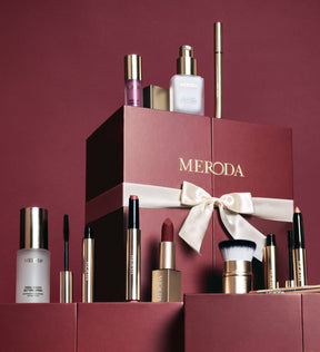 Burgunderroter Adventskalender mit weißer Satinschleife und verschiedenen Meroda Cosmetics Produkten.