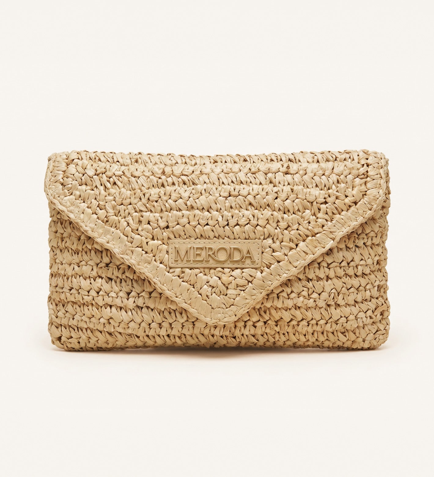 Summer Travel Clutch aus geflochtenem Papierstroh mit dreieckiger Klappe und Meroda-Logoplättchen.