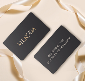 Meroda E-Gift Card: schwarze Karten mit goldenem Slogan Inspired by the Diversity of Humanity und Seidenband.